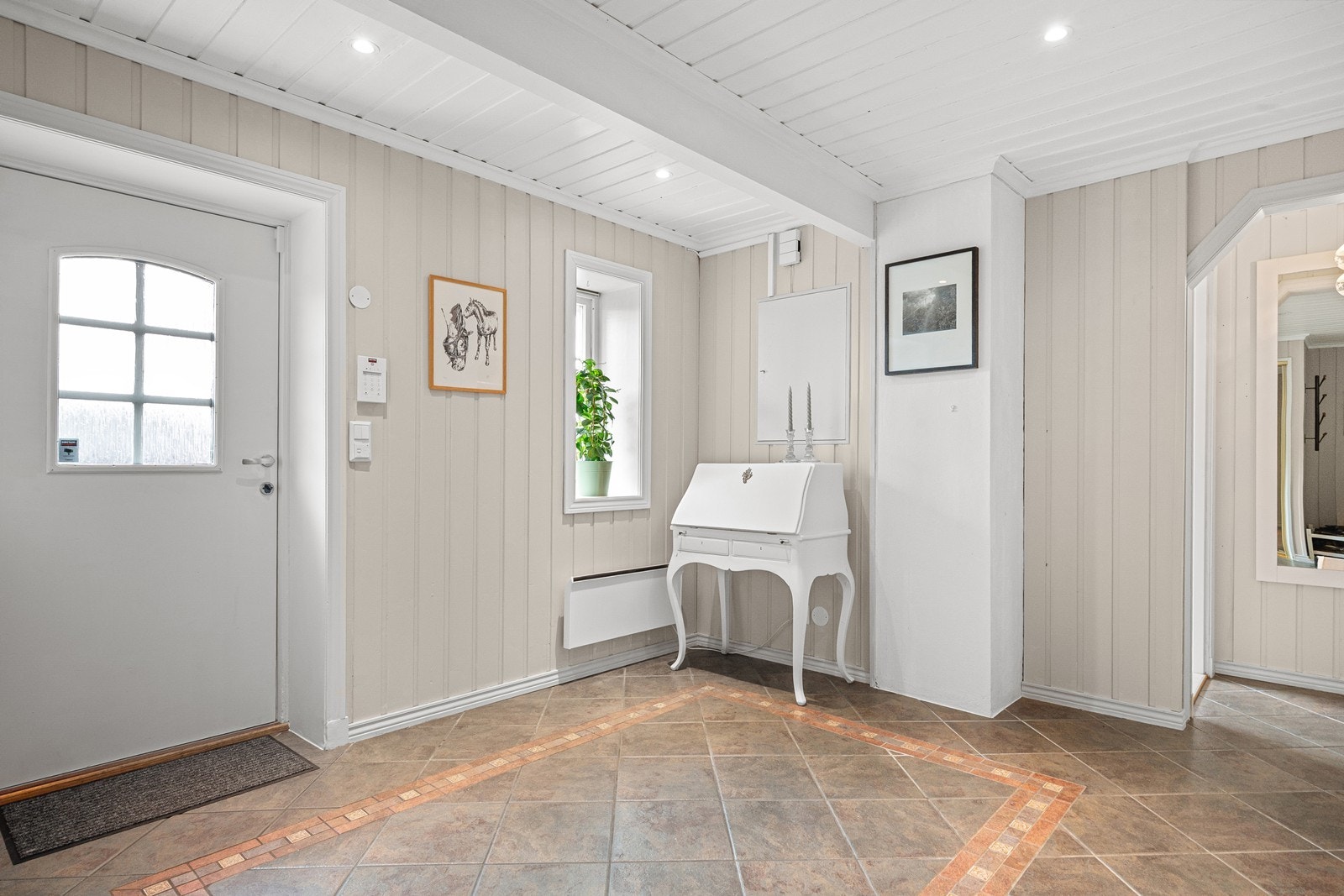 Velkommen inn i en romslig hall med flislagt gulv og downlights i taket. Galleribilde