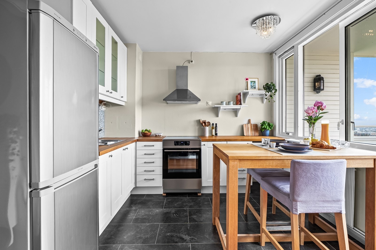 Kjøkkenet har en pen innredning fra Ikea med hvite, profilerte fronter og benkeplate i heltre med nedfelt kum. Galleribilde