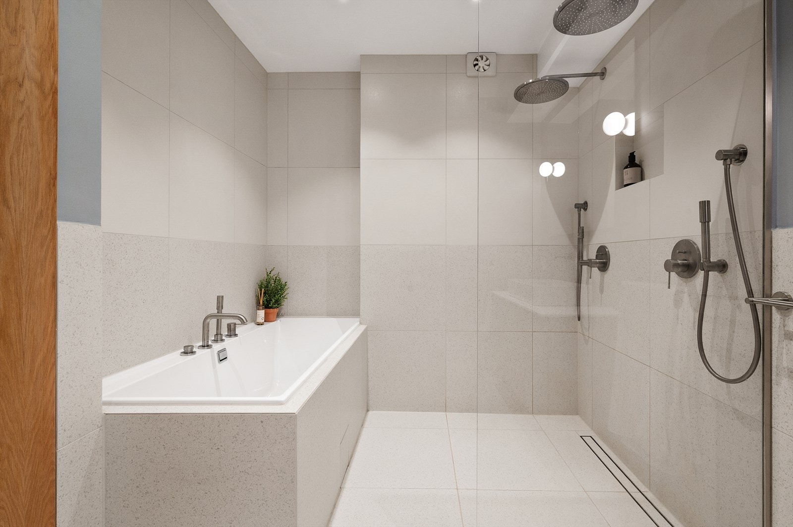 Romslig dusjsone med glassvegg og regnfallsdusj. I tillegg byr badet på et innbydende badekar som legger til rette for avslappende stunder etter en lang dag Galleribilde