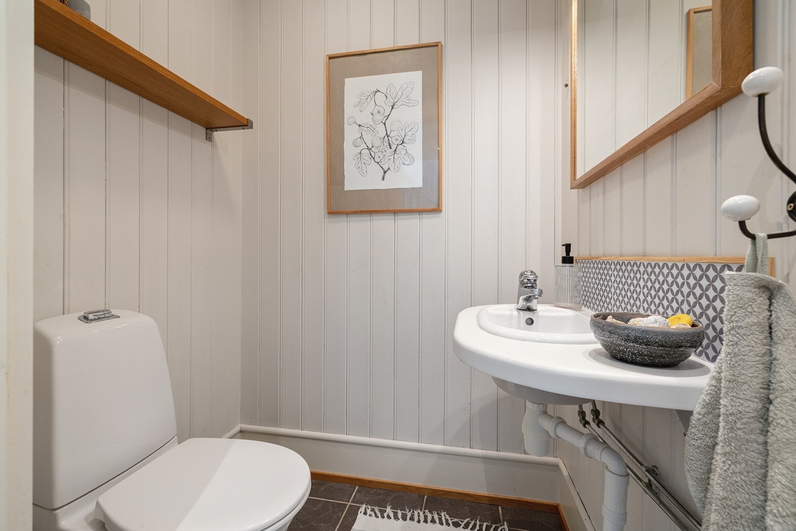 Praktisk toalettrom i første etasje med flislagt gulv og malt panel på veggene. Galleribilde