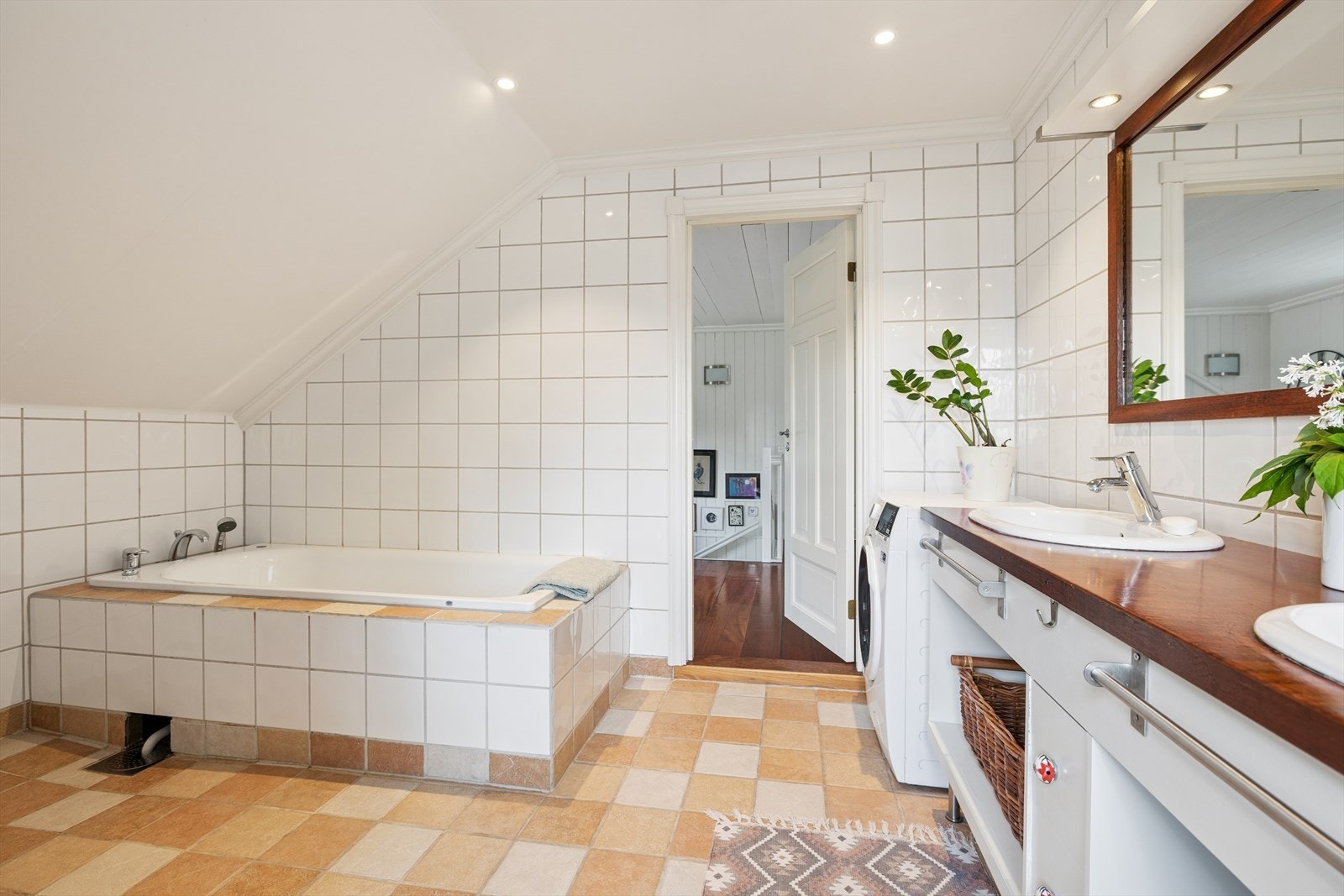 Badet er utstyrt med gulvstående toalett, dusjhjørne i glassbyggerstein, badekar samt to servanter med tilhørende innredning. Galleribilde