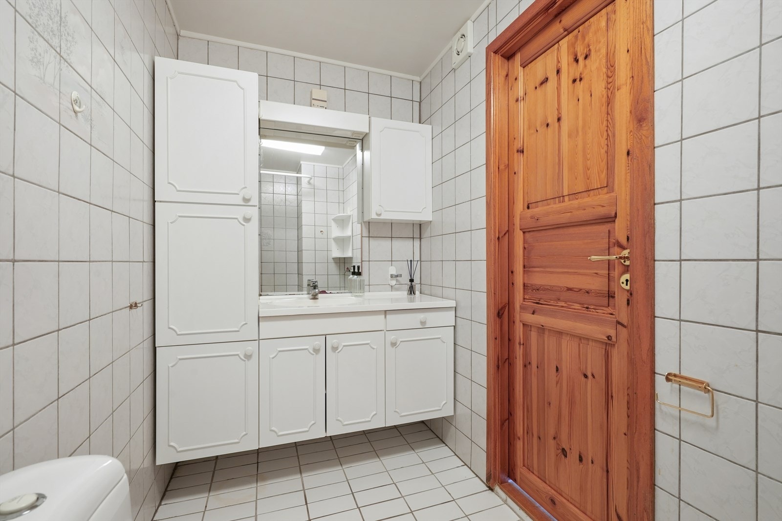 Bad/vaskerommet har fliser og varmekabler i gulv og flis på vegger. Utstyrt med dusj med forheng, toalett, hel servantplate med underskap, elektrisk avtrekk og opplegg for vaskemaskin. Galleribilde