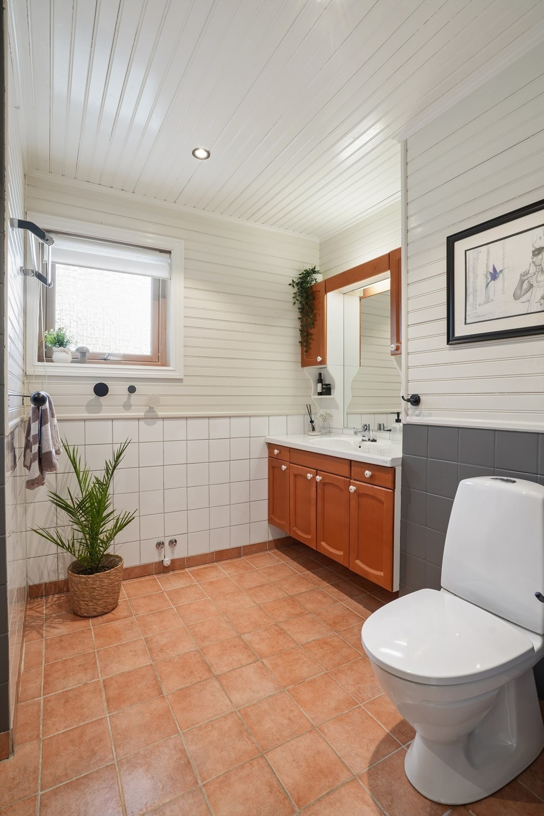 Badet har fliser og varmekabler i gulv, flis og panel på vegger, og panel i himling. Utstyrt med dusjkabinett, toalett og hel servantplate med underskap. Galleribilde