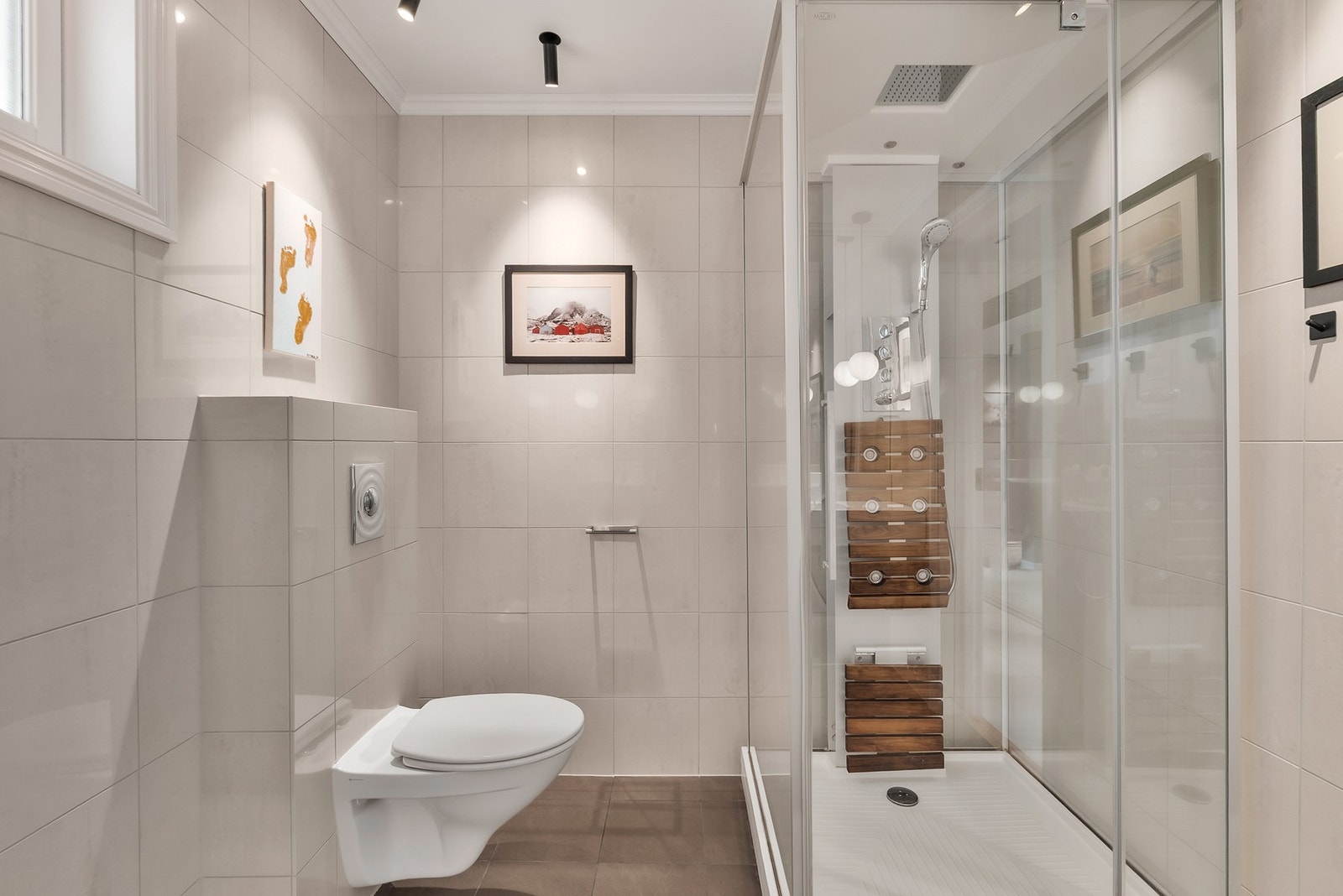 Badet er utstyrt med veggmontert toalett og dusjkabinett. Galleribilde