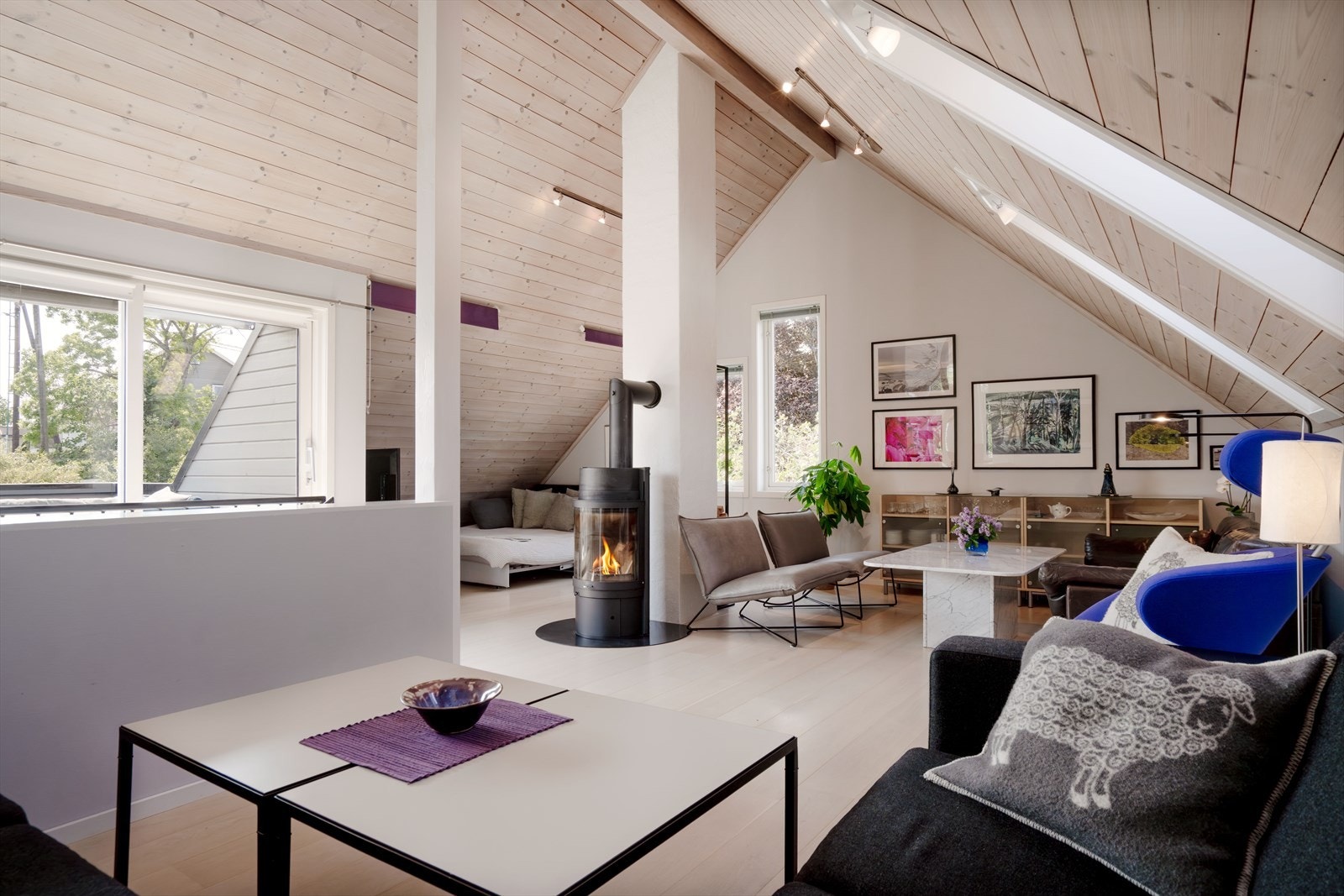 Lys og romslig loftstue med åpen løsning, god takhøyde og moderne peisovn som skaper en lun atmosfære. Galleribilde