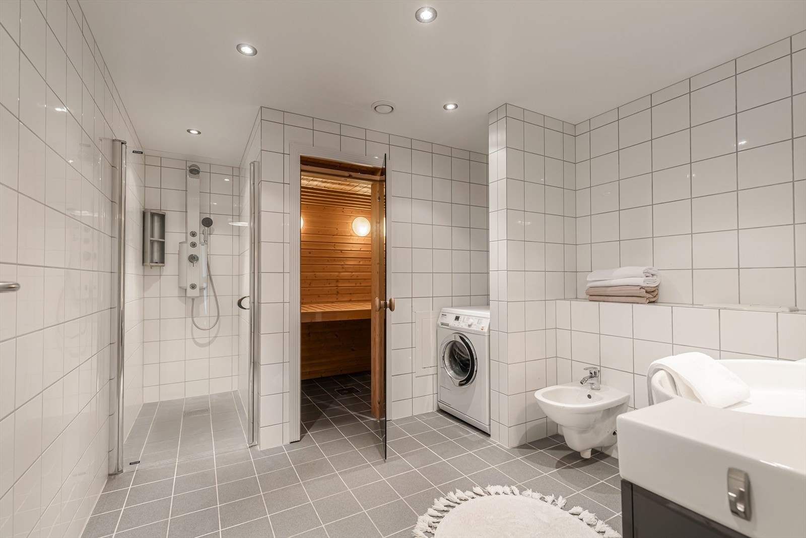 Badet er av meget god størrelse, og inneholder dusjnisje med blandebatteri med flere funksjoner, badstue, opplegg for vaskemaskin, bidé og servantinnredning Galleribilde
