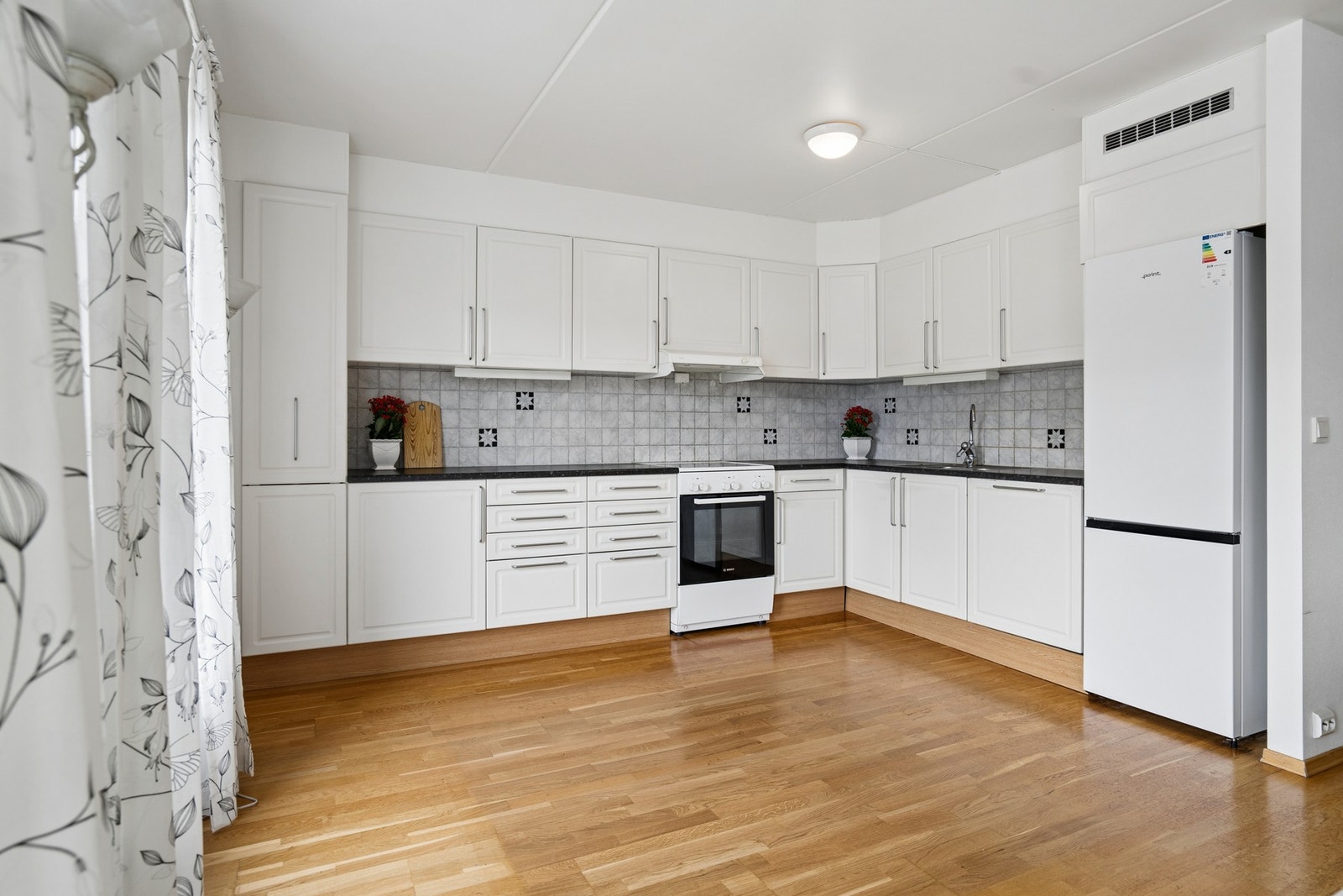 Kjøkkenet har en praktisk hjørneløsning med laminert benkeplate og profilerte fronter. Det er utstyrt med frittstående hvitevarer. Galleribilde
