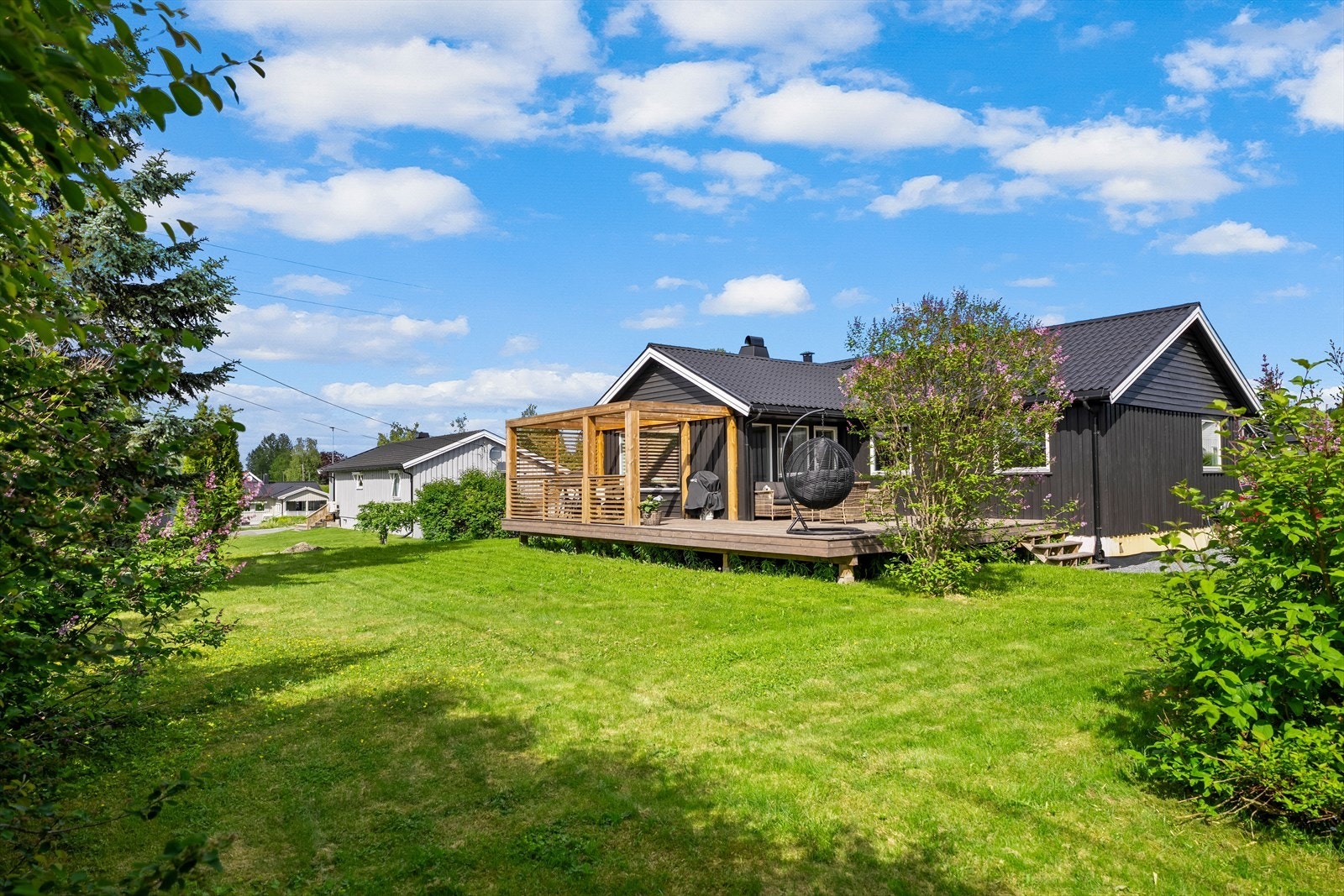 Romslig og pent opparbeidet tomt med store plenarealer, frodig beplantning og en innbydende terrasse. Galleribilde
