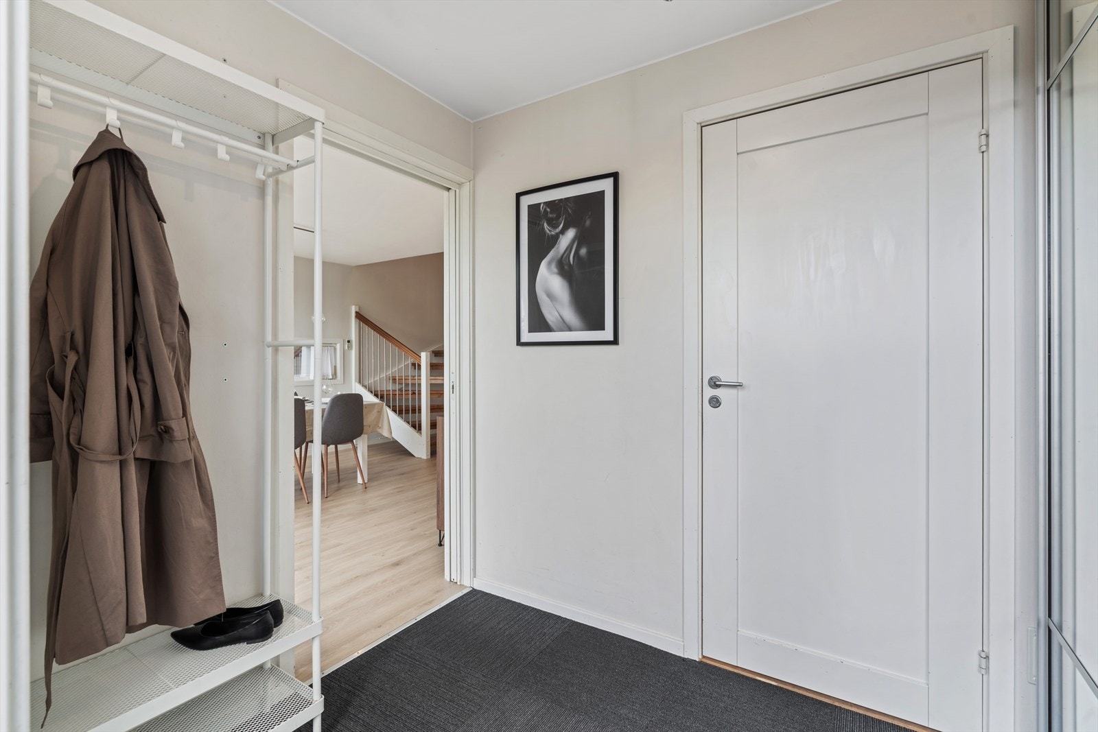 Romslig entré med rikelig plass til oppbevaring av klær og sko. Praktisk og lettstelt teppe som sørger for enkel vedlikehold Galleribilde