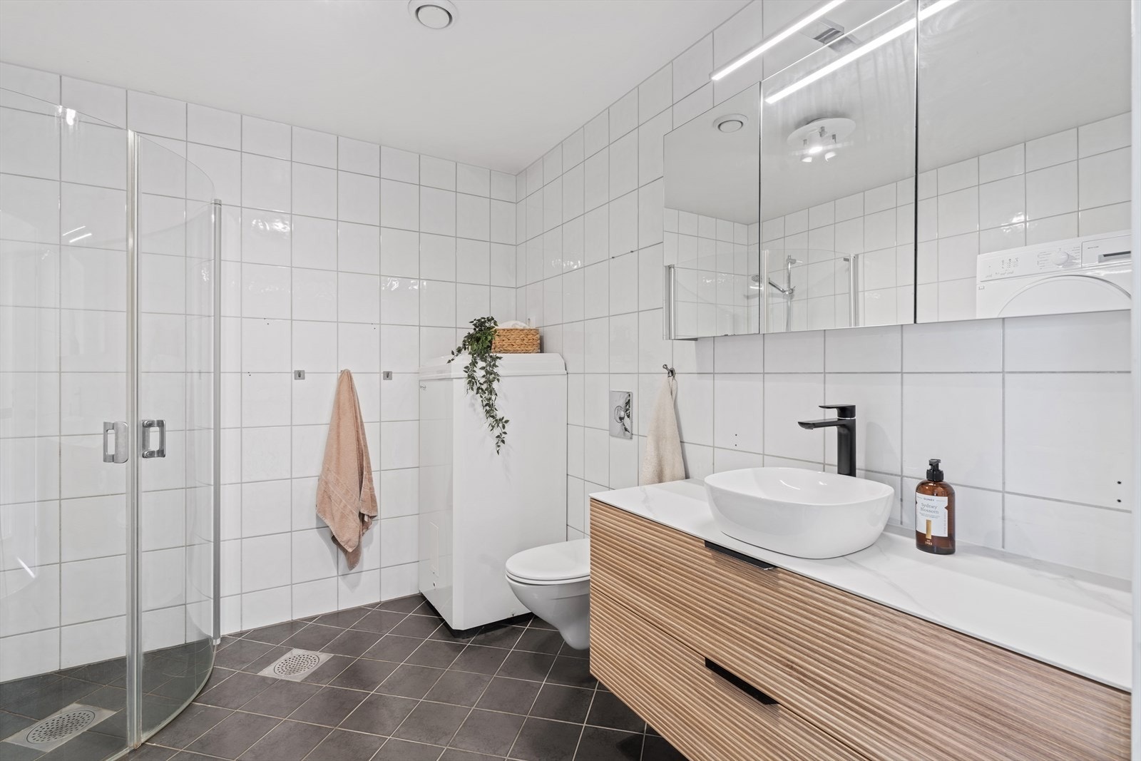 Helfliset og moderne bad med gulvvarme, nedfelt servant, toalett, dusjdører og balansert ventilasjon Galleribilde