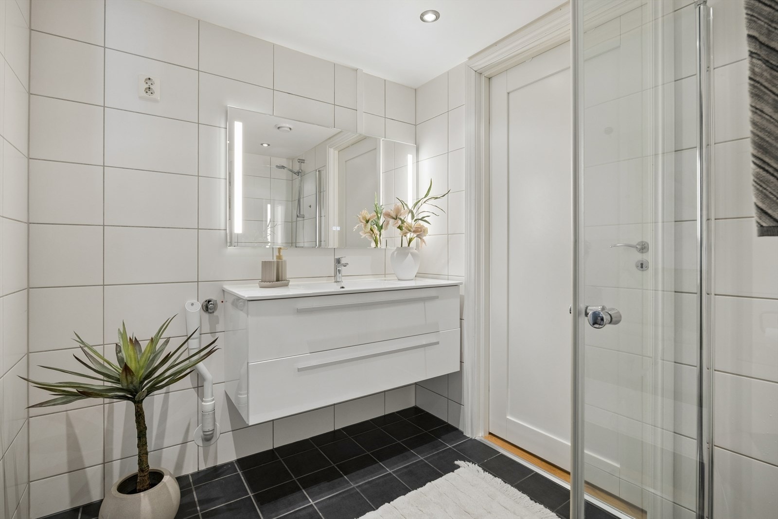 Innredningen består av servant, veggmontert toalett og dusjhjørne med glassdører. Fra badet er det inngang til teknisk rom. Galleribilde