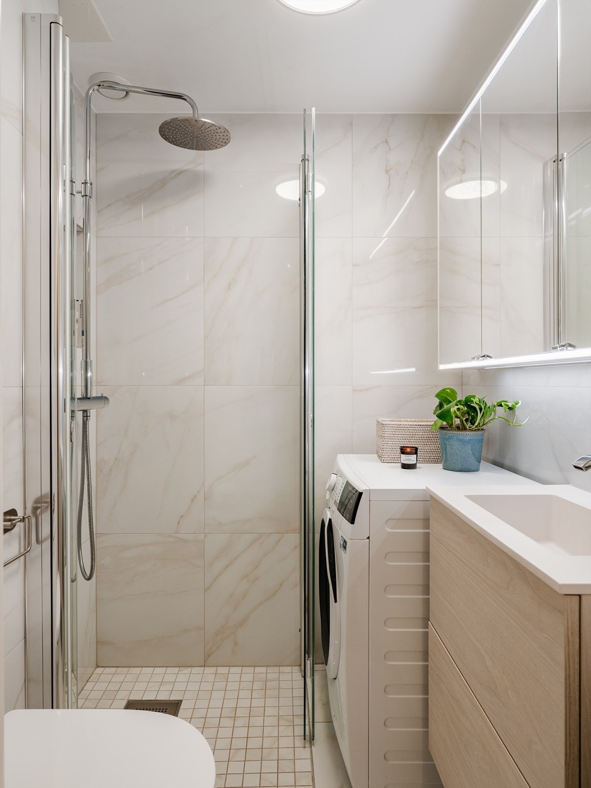 Badet fremstår moderne og funksjonelt, med en innredning bestående av benkeskap og veggskap med glatte fronter, samt overskap med speilfronter. Galleribilde