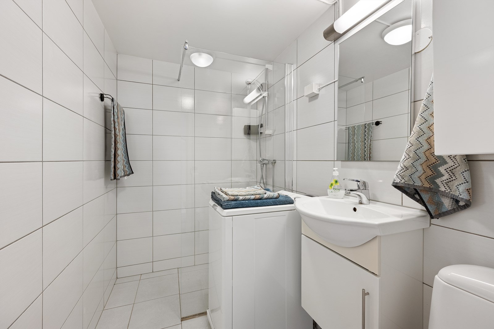 Funksjonelt bad med gulvvarme, dusjhjørne med glassvegg og opplegg for vaskemaskin. Galleribilde