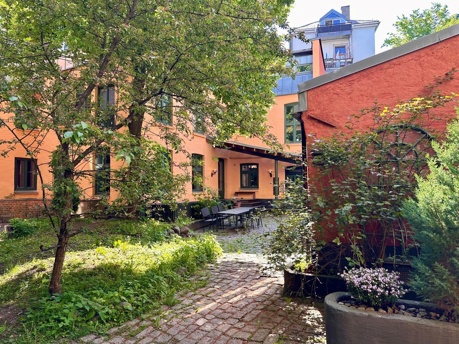 Sjarmerende og skjermet bakgård med grønne omgivelser, hyggelige sitteplasser og en lun atmosfære midt i byen. Galleribilde
