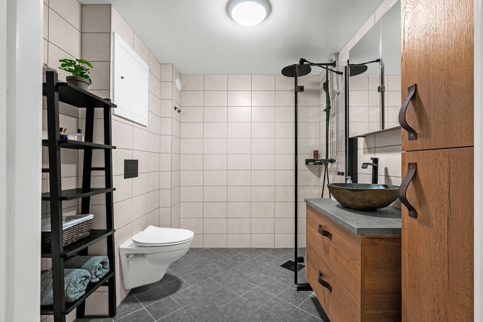 Badet har flislagte gulv og vegger i nøytrale farger. Galleribilde