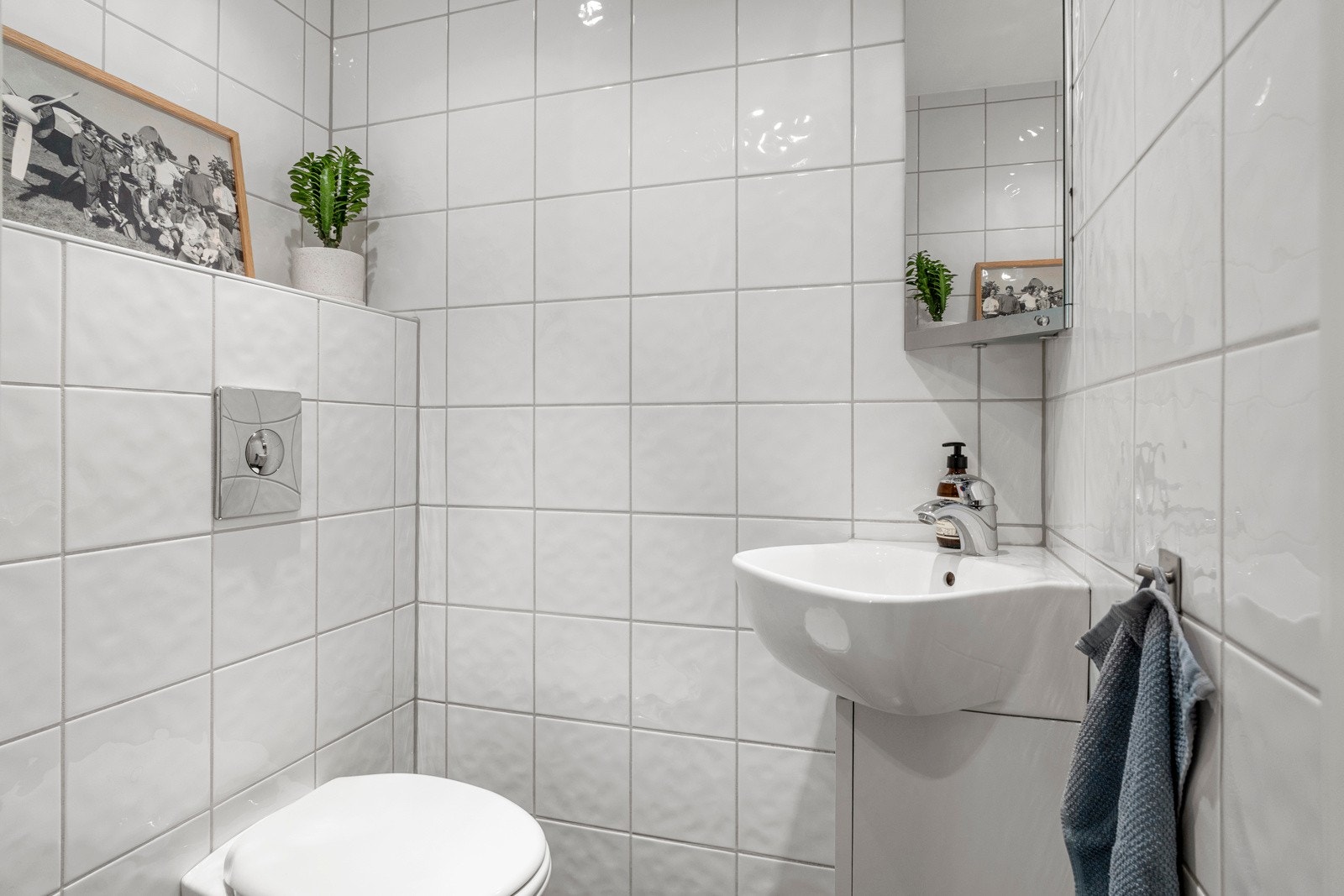 WC-rommet fremstår lyst og innbydende, med vegghengt toalett og servant. Rommet er flislagt i lyse, tidløse toner og har behagelig gulvvarme for økt komfort Galleribilde