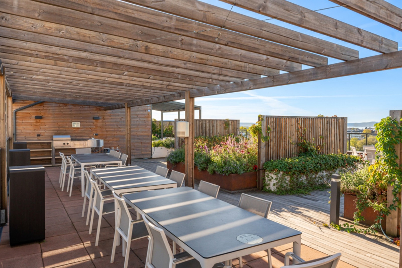 Takterrasse utstyrt med to utekjøkken og vask med mulighet for grilling og sosiale lag sene sommerkvelder. En grønn oase med både urter og blomster. Galleribilde