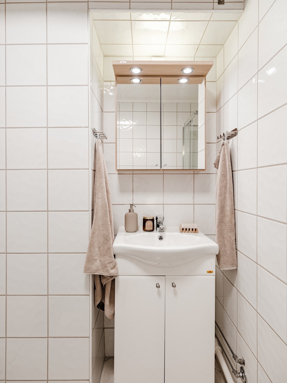 Badet er innredet med servant i benkeskap og speilskap for oppbevaring. Galleribilde