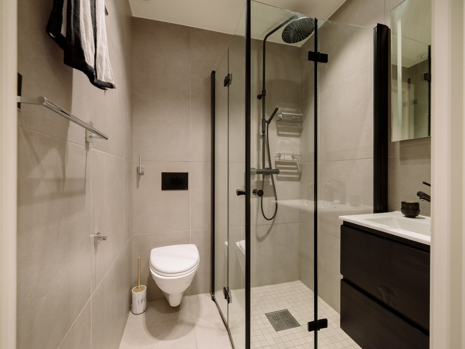 Badet i 1.etasje er utstyrt med dusjhjørne med glassdører, vegghengt toalett, servant med underskap og speilskap. Galleribilde