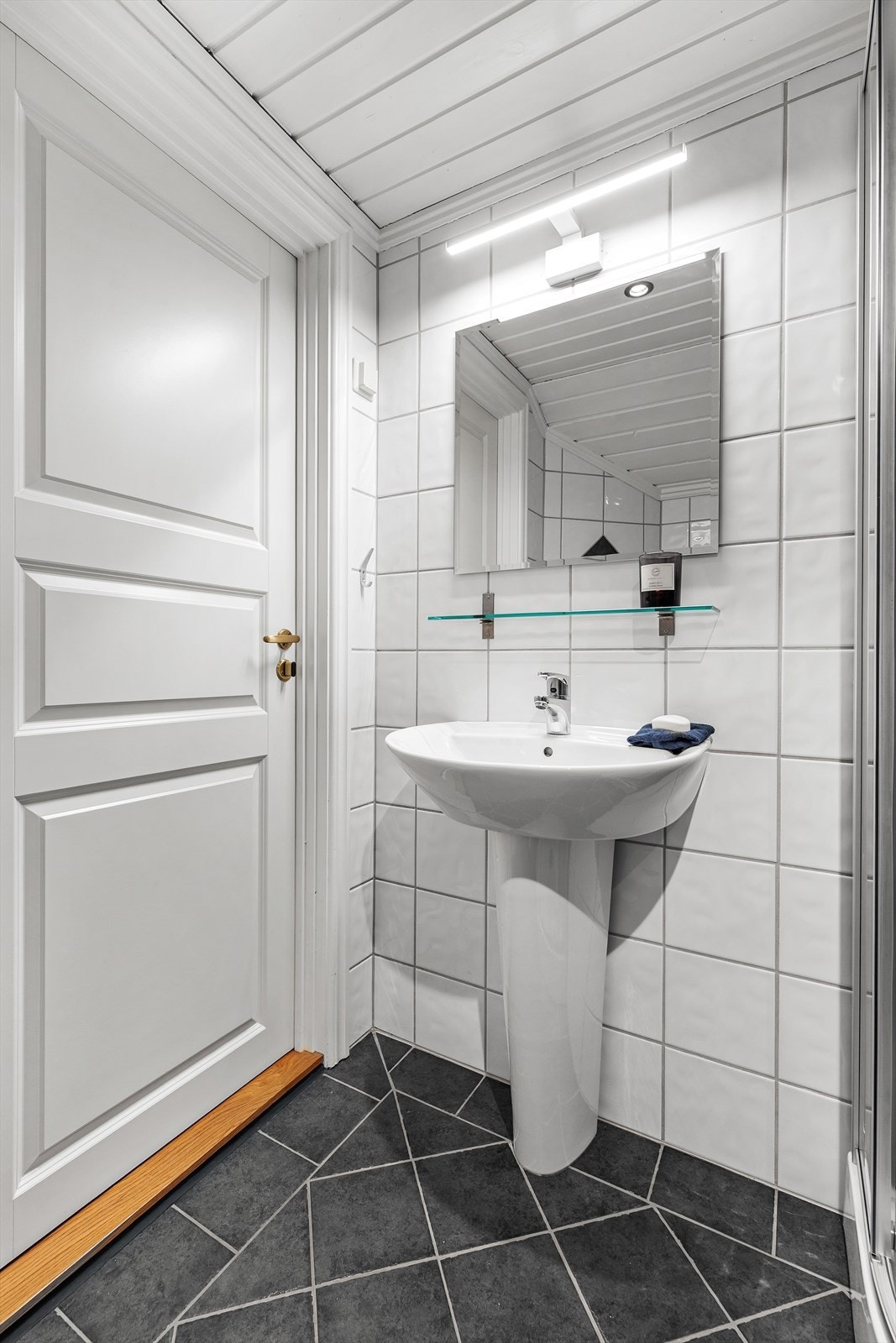 Badet er utstyrt med servant, toalett og dusjkabinett. Rommet er fra da loftet ble innredet i 2012. Galleribilde