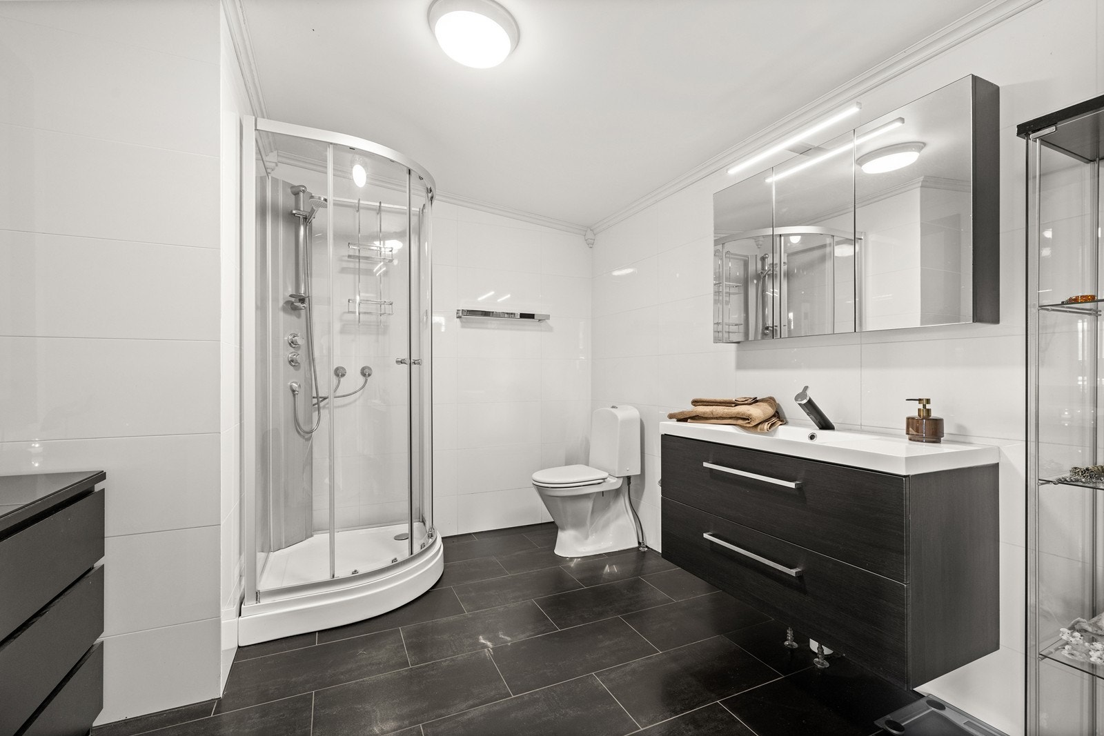 Badet i første etasje med fliser på gulv og vegger, dusjkabinett og gulvvarme. Galleribilde