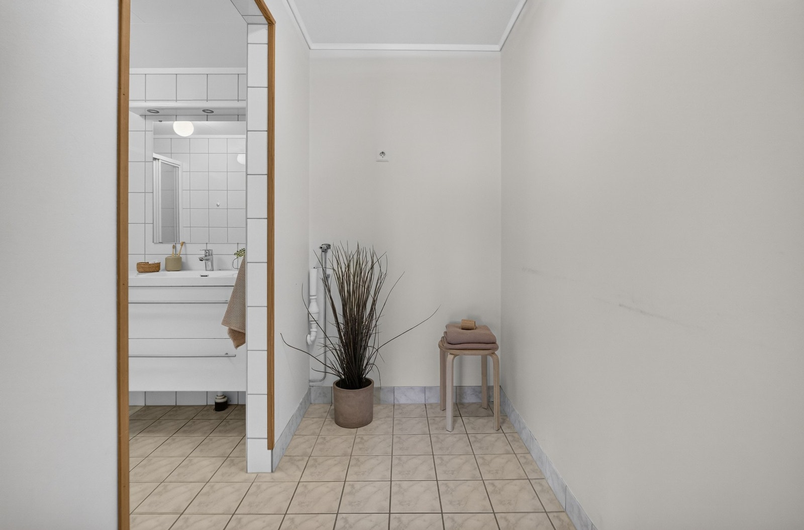 Utenfor badet er det et eget rom med fliser på gulv og opplegge for vaskemaskin. Galleribilde