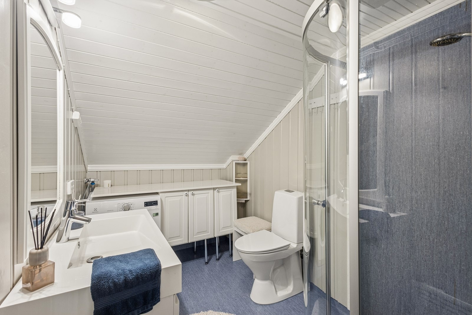 Badet i loftsetasjen er utstyrt med dusjdører, servant med underskap og opplegg for vaskemaskin. Vaskemaskin medfølger. Galleribilde