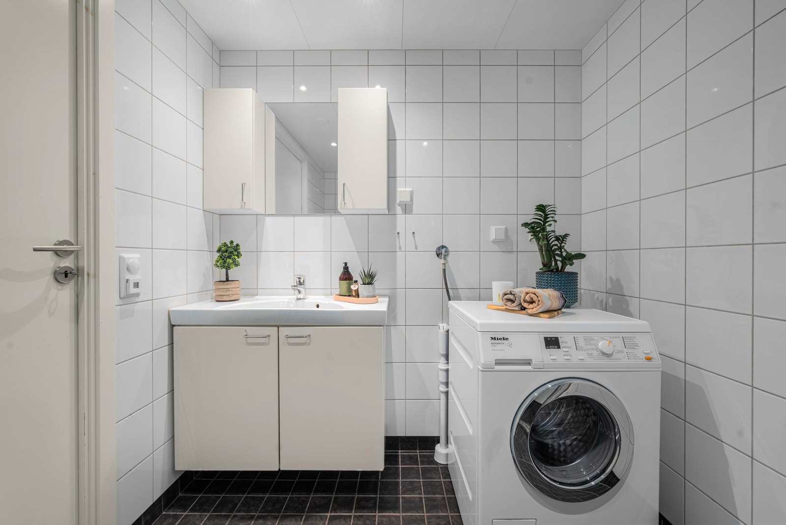 Leiligheten har et lyst og moderne baderom fra byggeåret 2012. Baderommet har mørke fliser på gulv, elektrisk gulvvarme, hvite fliser på veggene, downlights i himlingen og mekanisk avtrekk. Galleribilde