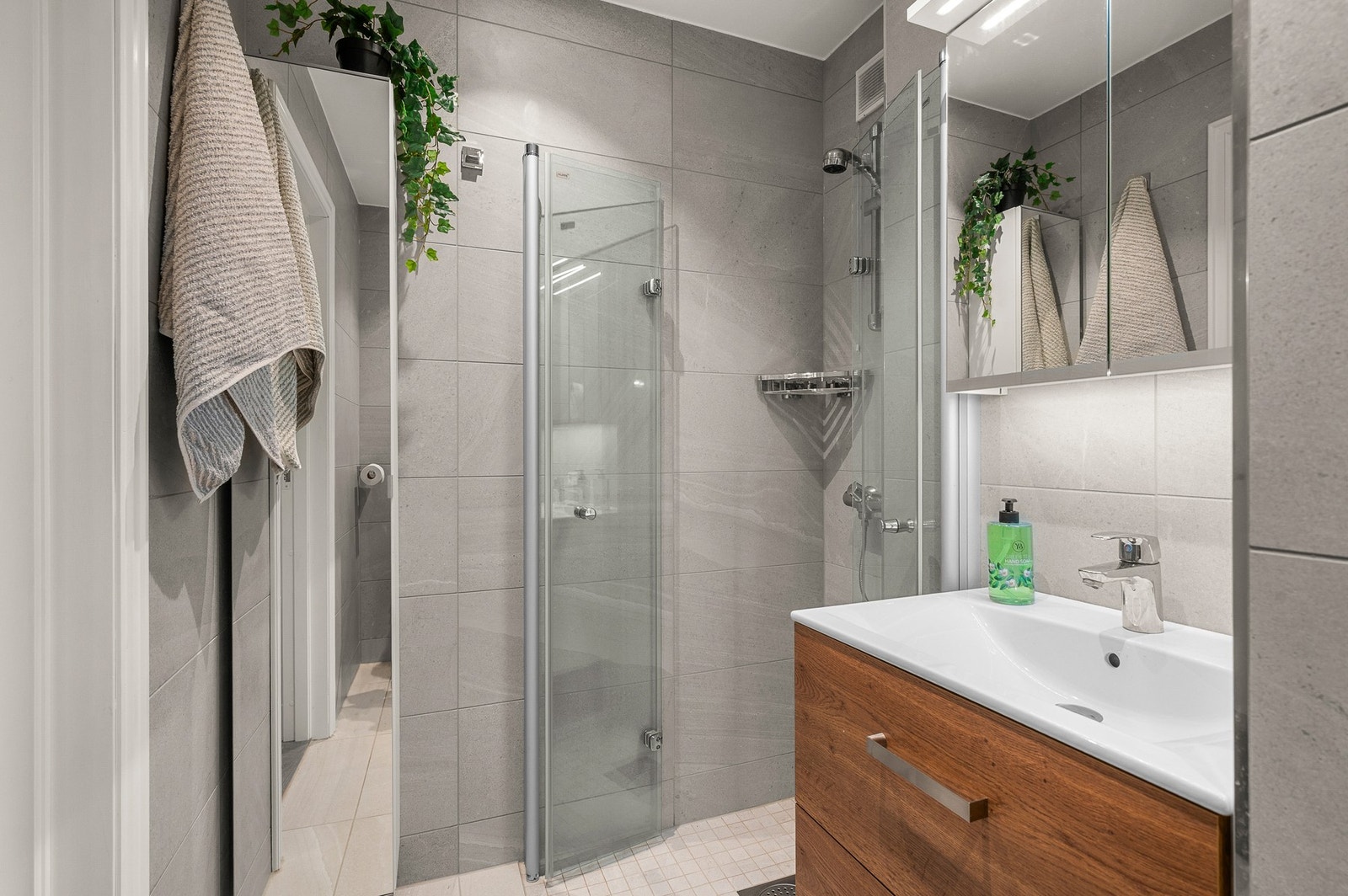 Badet er utstyrt med dusjnisje, servant med skuffer, speilskap og vegghengt toalett. Galleribilde