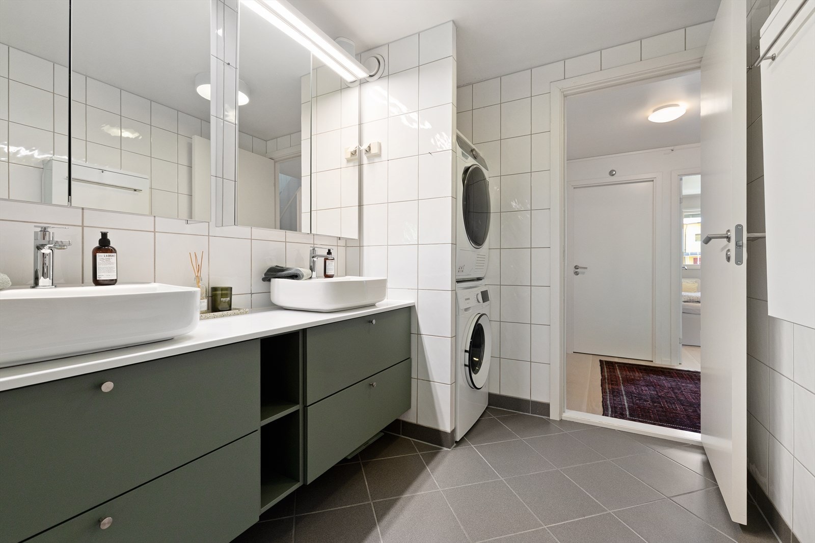 Badet er utstyrt med badekar og innfellbar dusjløsning, hånddusj og regndusj. Baderomsinnredningfra 2023 bestående av stilren innredning på 180 cm med grønne skuffefronter. Dobbelservant med ettgreps armatur fra Kohlman. Elektrisk håndkletørker. Galleribilde
