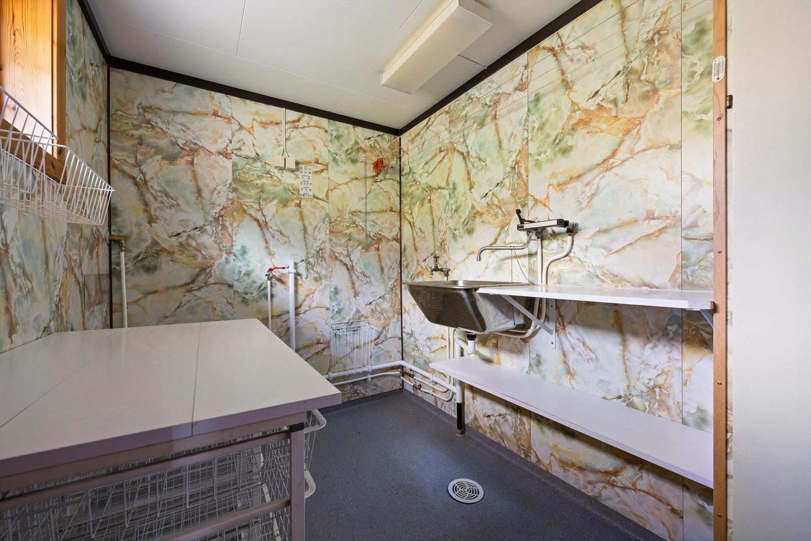 Praktisk vaskerom ved inngangspartiet, utstyrt med skyllekar og opplegg for vaskemaskin. Galleribilde