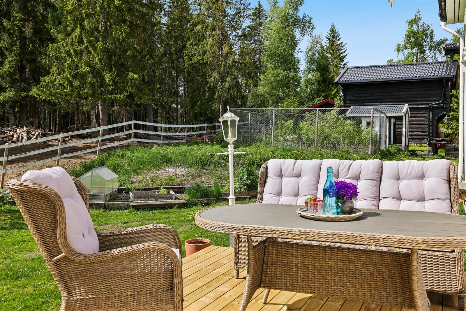 Fra terrassen er det utsikt over hagen og de omkringliggende områdene. I bakgrunnen ses hundegården med isolert/oppvarmet "hunderom". Galleribilde
