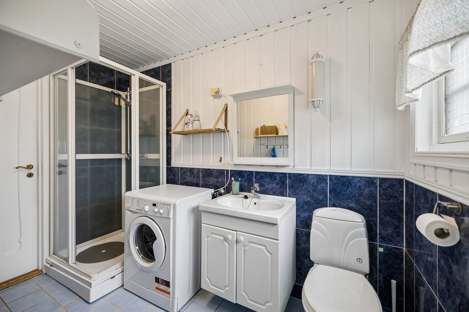 Badet i kårboligen har fliser med varmekabler på gulv og opplegg for vaskemaskin. Galleribilde