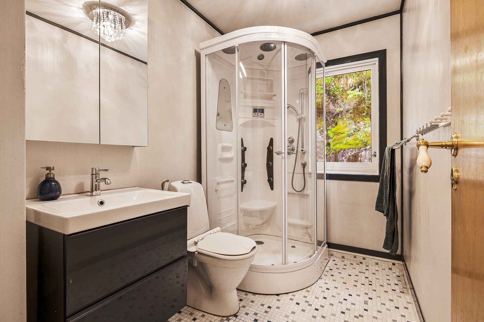 Badet er utstyrt med servantmøbel, toalett og dusjkabinett. Det er avtrekksventil i himlingen. Galleribilde