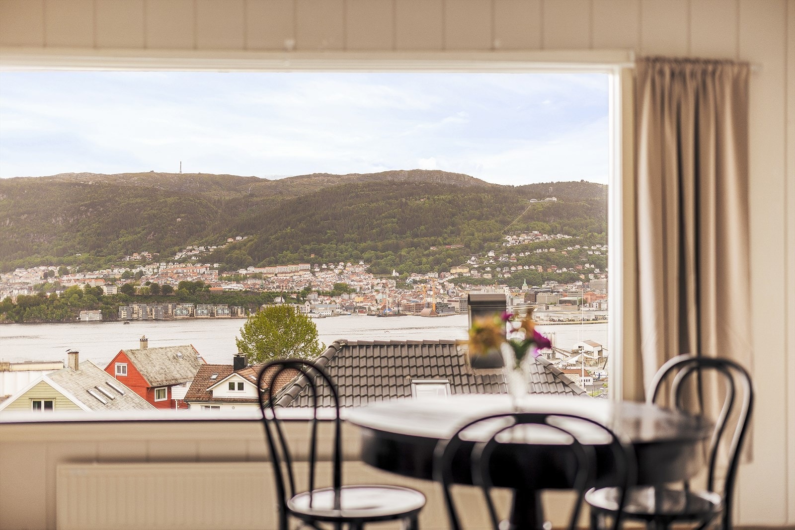Nyt utsikten mot byfjellene fra stuevinduet. Galleribilde