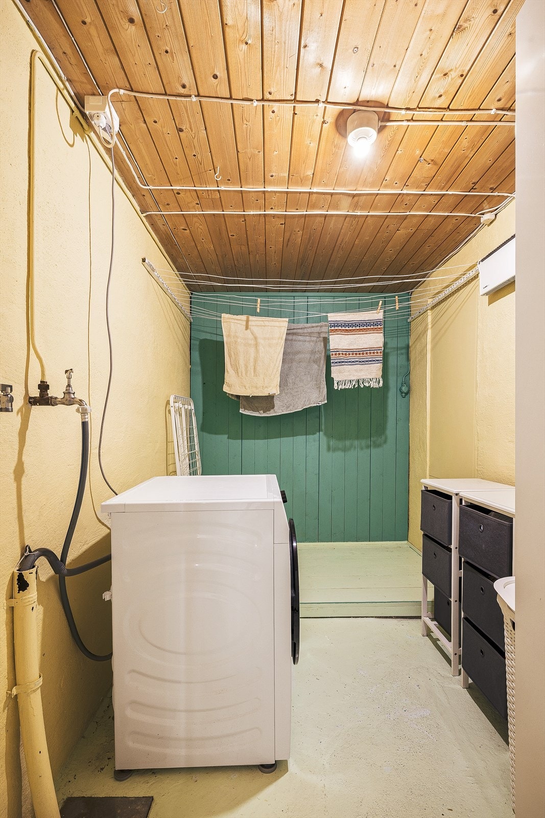 Praktisk vaskerom med opplegg for vaskemaskin og avtrekksventil i veggen. Galleribilde