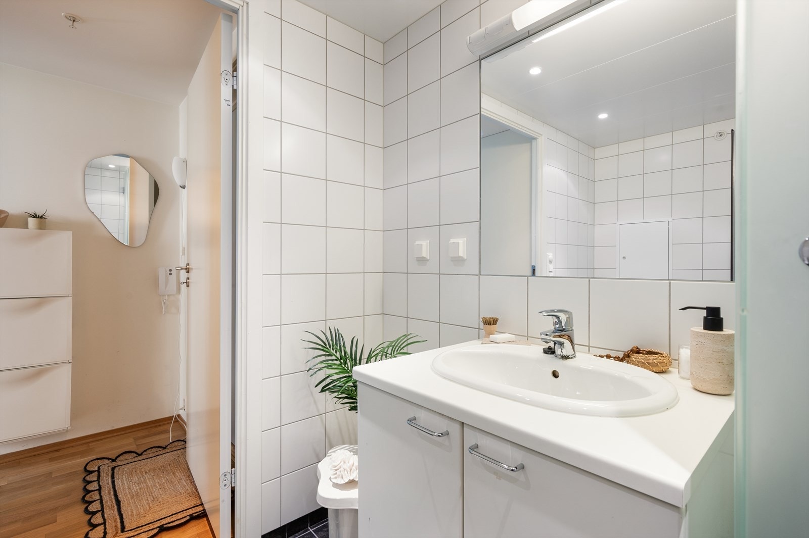 Ellers er badet innredet med baderomsinnredning med oppbevaring og vegghengt speil med belysning over. Galleribilde