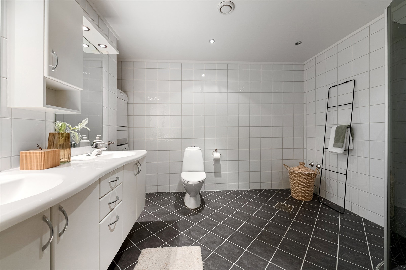 Romslig og moderne bad med stilrene fliser og praktisk innredning. Galleribilde