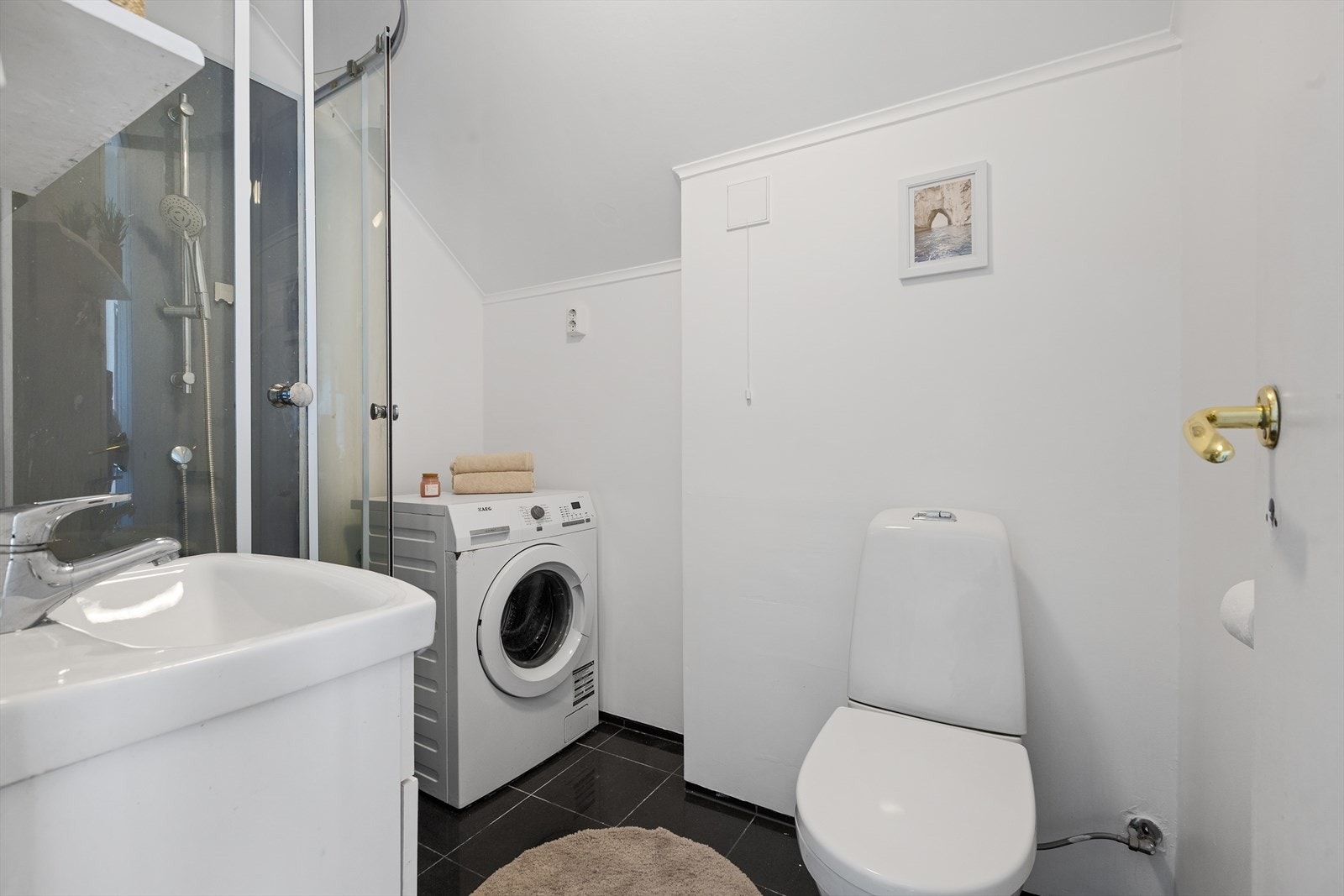 Badet har fliser på gulv og malte vegger- installert dusjkabinett, toalett og baderomsinnredning- opplegg til vaskemaskin Galleribilde