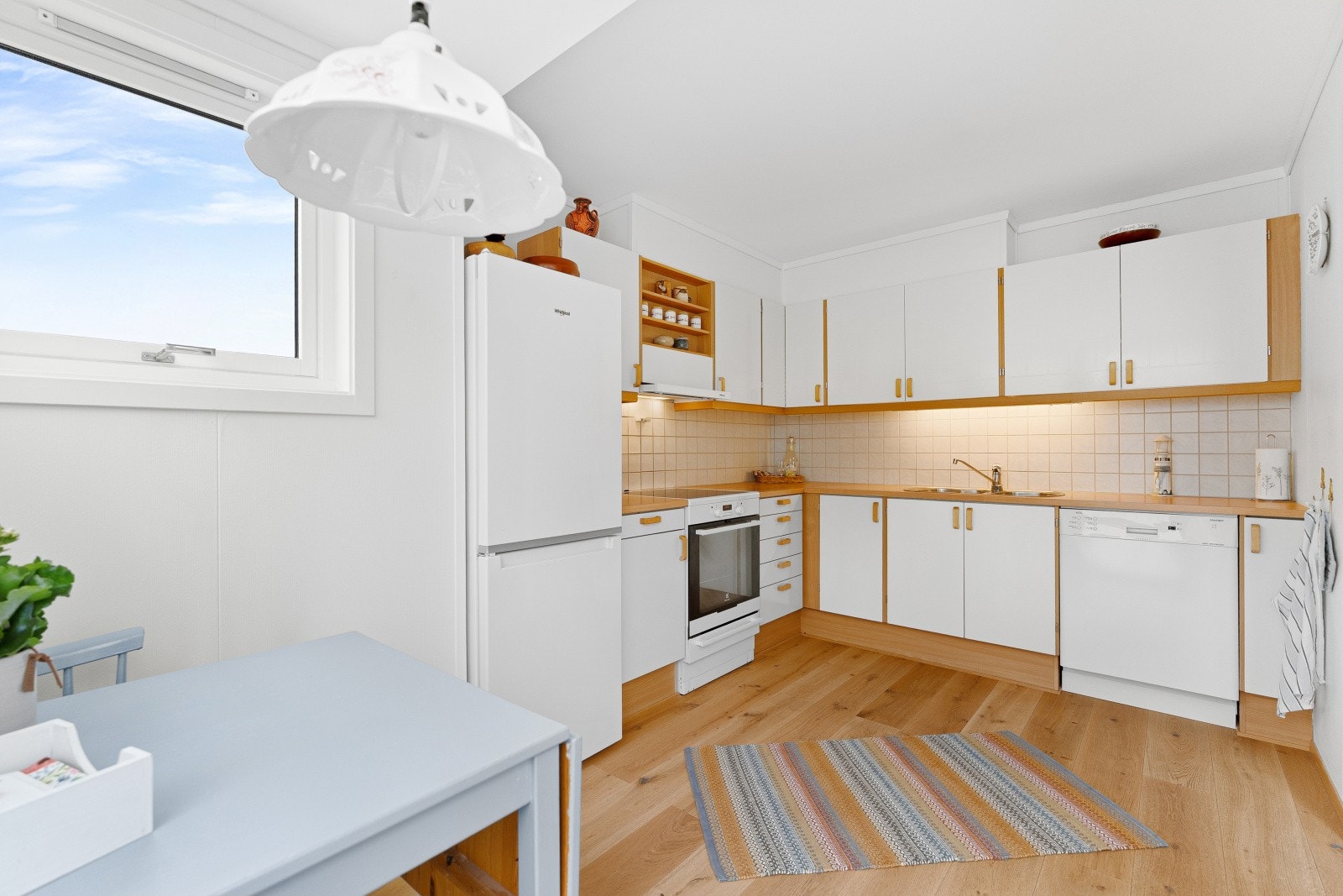 Lyst og velholdt kjøkken som har godt med skap og benkeplass. Galleribilde