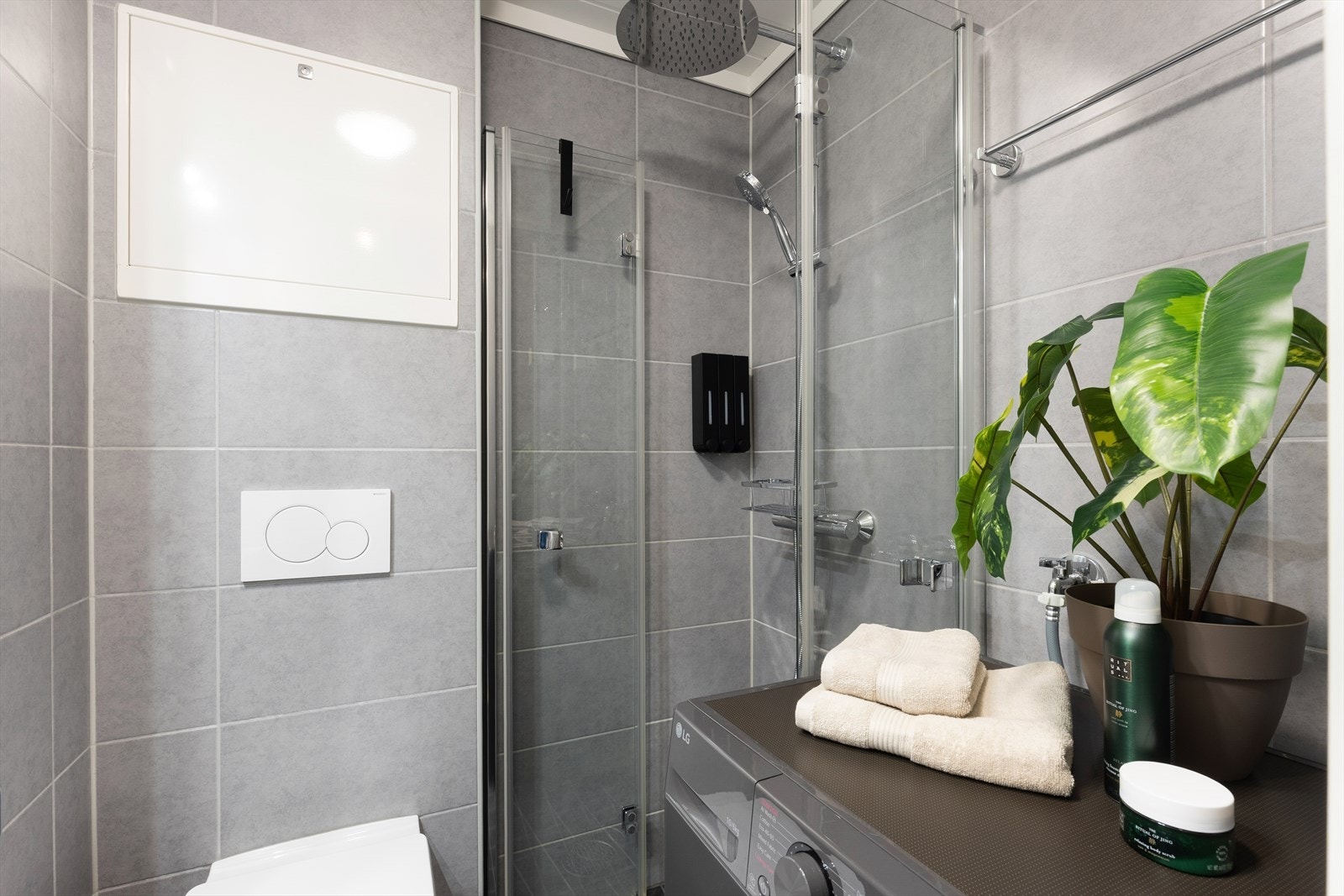 Badet er praktisk innredet med vegghengt toalett, dusjhjørne med innfellbare glassdører og opplegg for vaskemaskin. Galleribilde