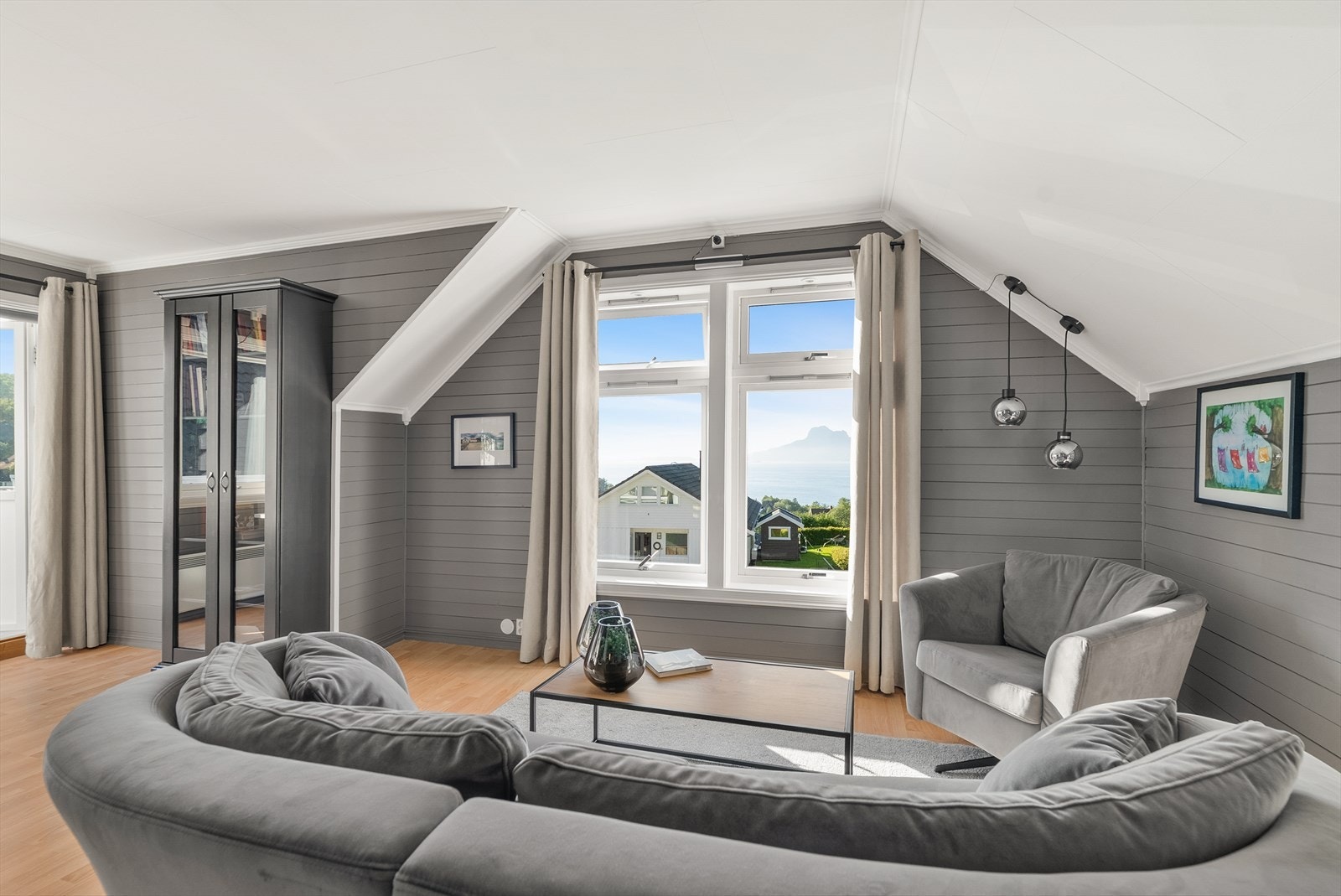 Stuen har skrå vegger og tak som følger takformen, og vinduer mot nærområdet og havet. Herfra er det utgang til takterrassen. Galleribilde