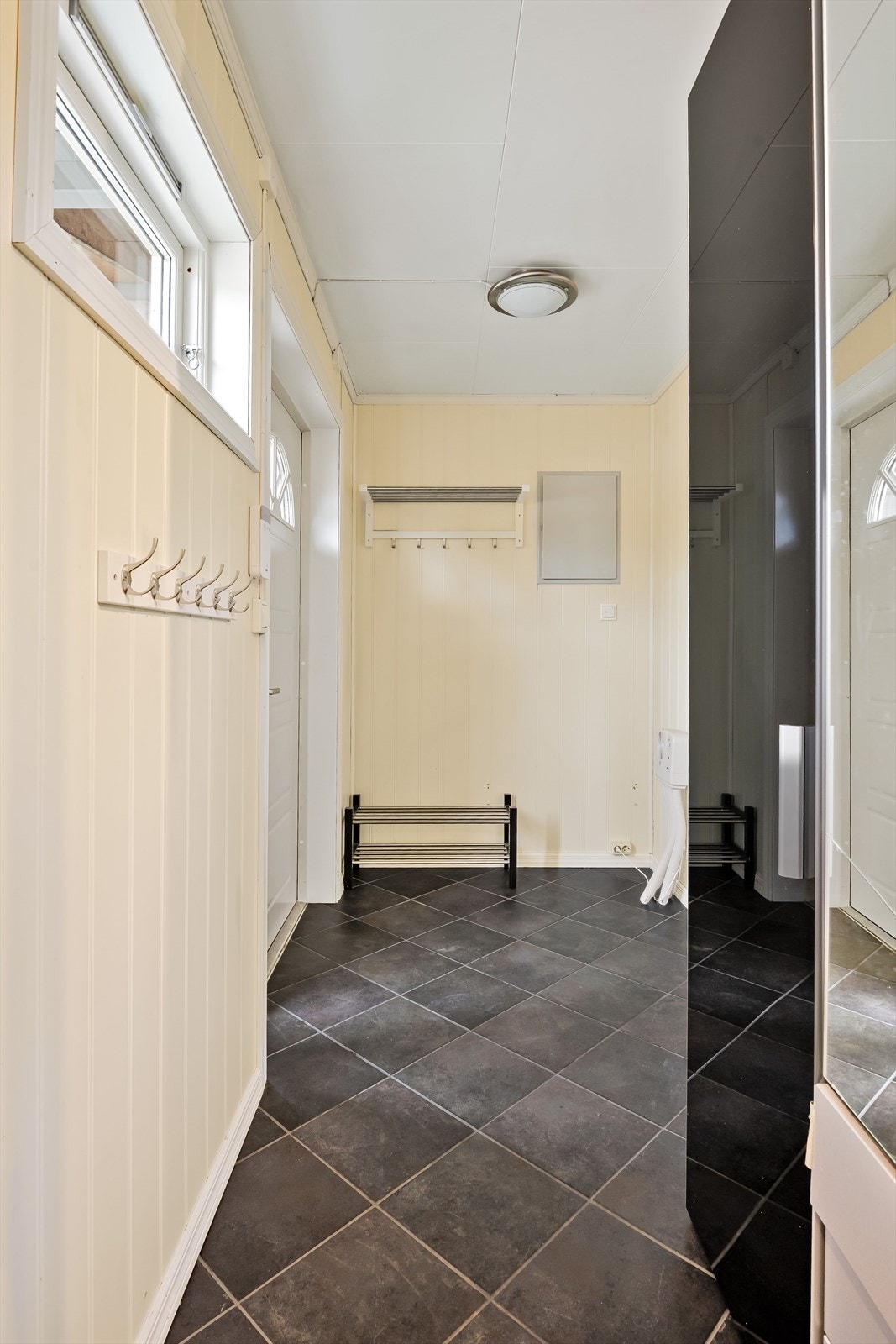 Flislagt gang med plass til garderobeskap. Det er også adkomst til vaskerommet fra gangen. Galleribilde