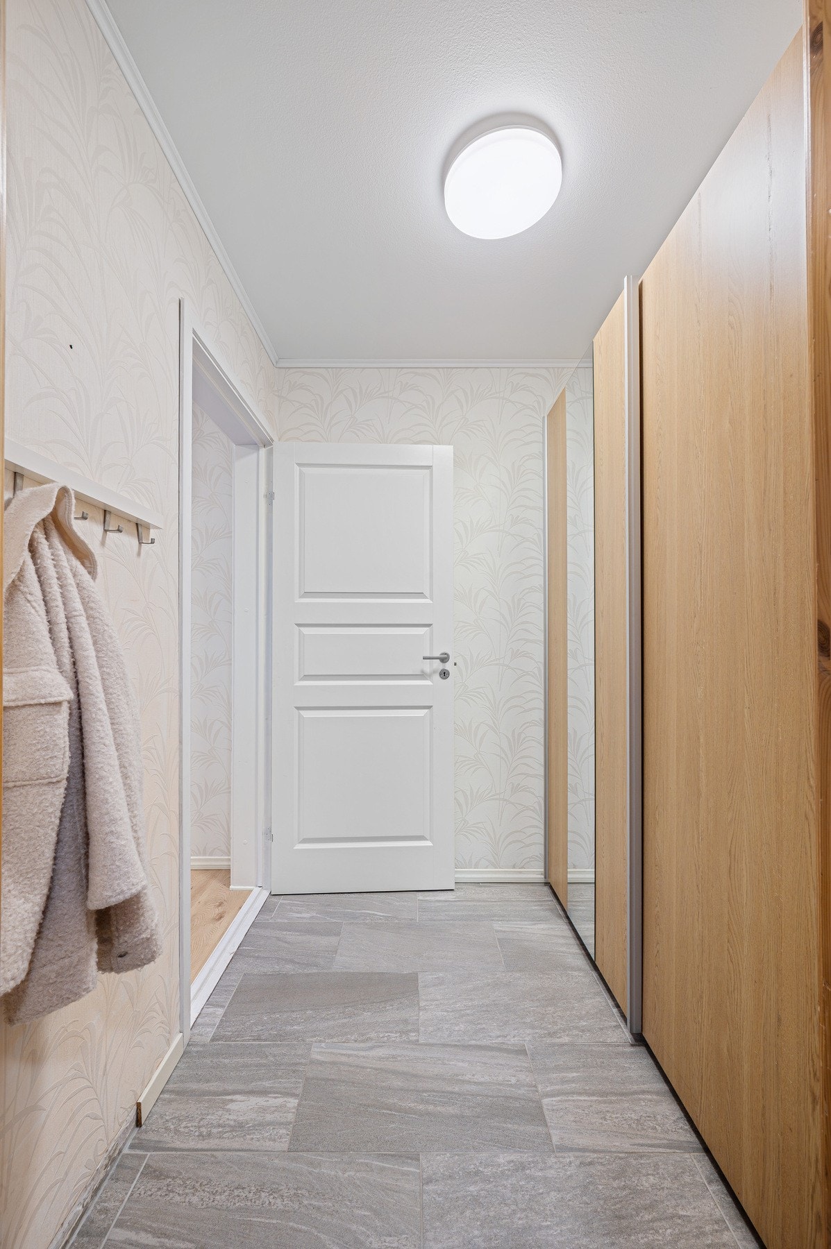 Velkommen inn! Leilighetens førsteinntrykk er en romslig entré på 3,4m² med en praktisk skyvedørsgarderobe. Galleribilde