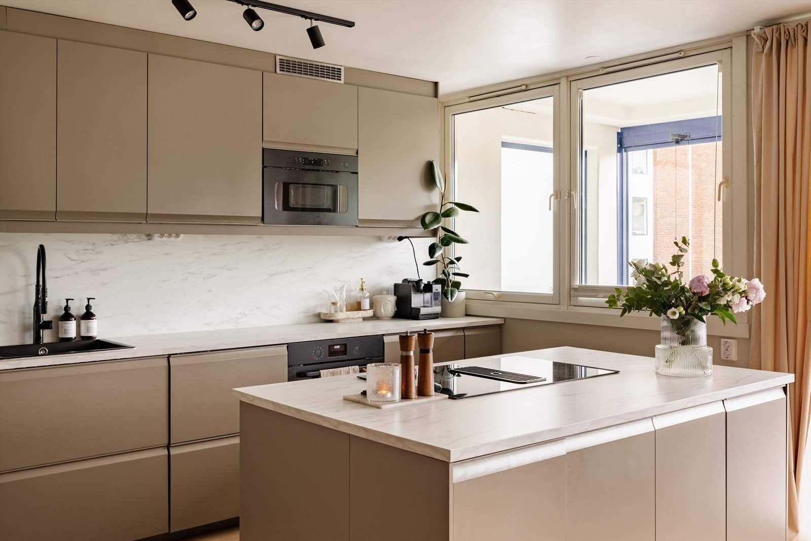Kjøkkenet fra 2024 fremstår stilrent og tidsriktig med elegante, beige slette fronter fra IKEA som harmonerer flott med leilighetens moderne uttrykk. Galleribilde