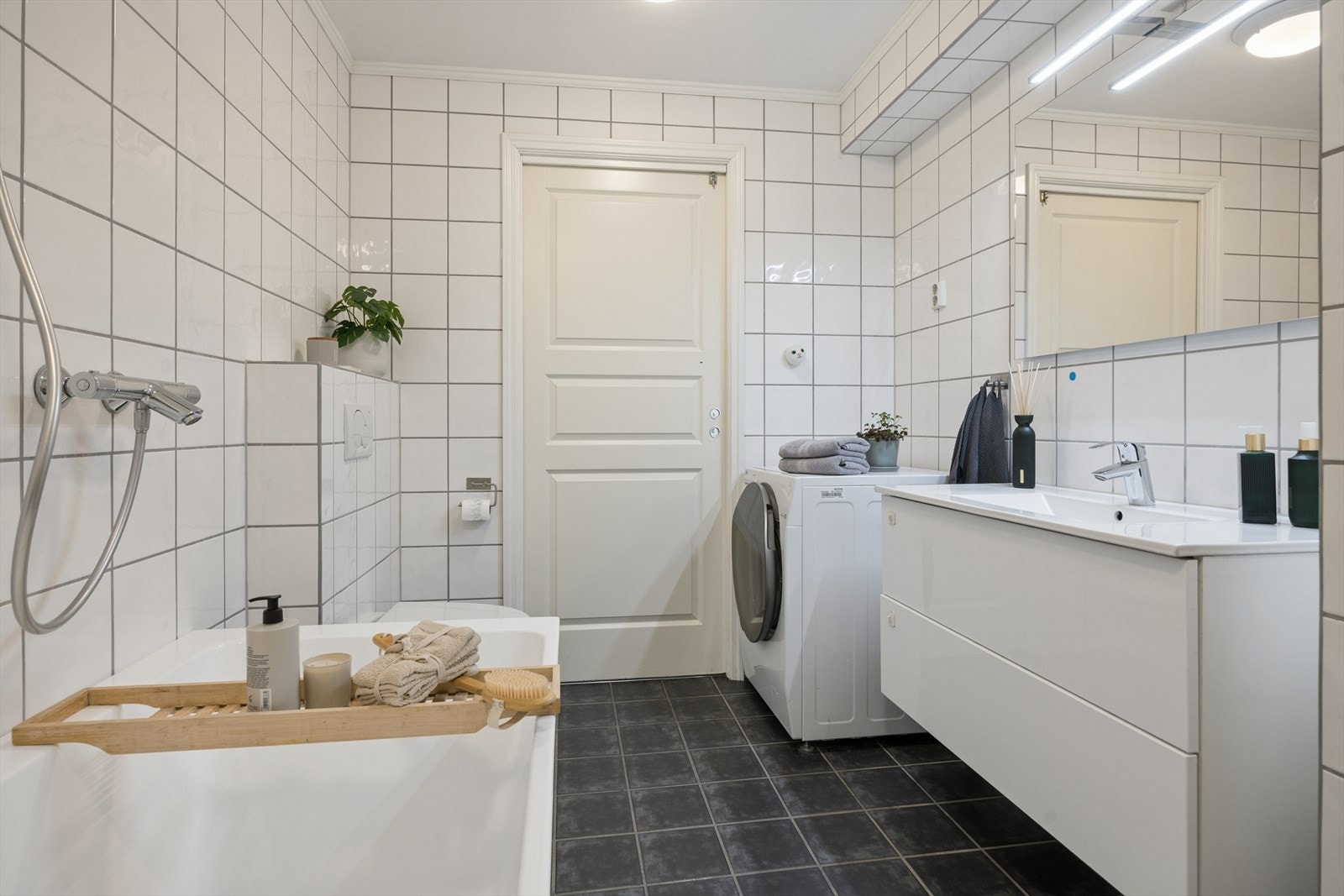 Helfliset bad med moderne badekar og praktisk opplegg for vaskemaskin. Galleribilde