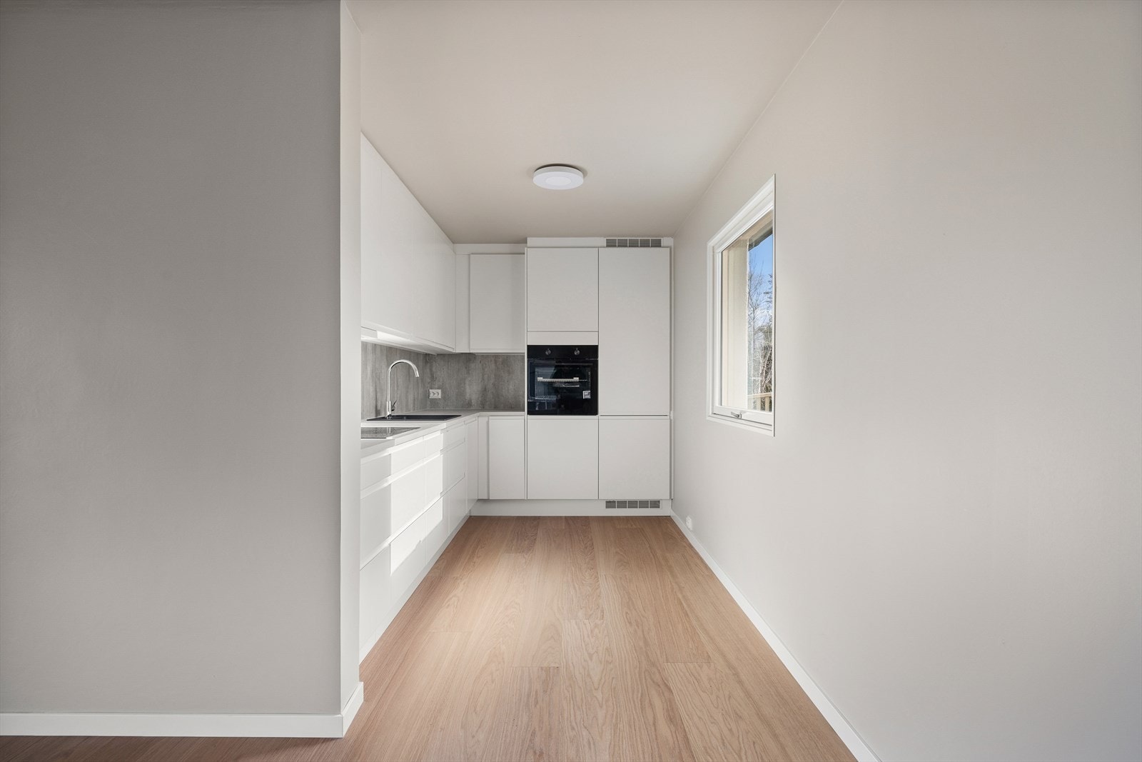Kjøkkeninnredningen er av glatte fronter, laminat benkeplate med nedfelt vaskekum. Det belysning og splashboard over benkeplaten. Galleribilde