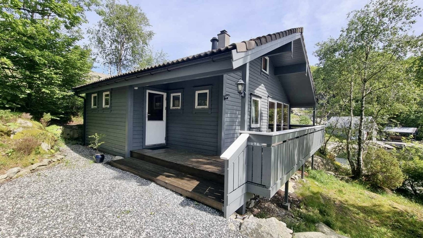 Terrassen strekker seg fra inngangspartiet og videre rundt fremsiden av huset til stuen Galleribilde