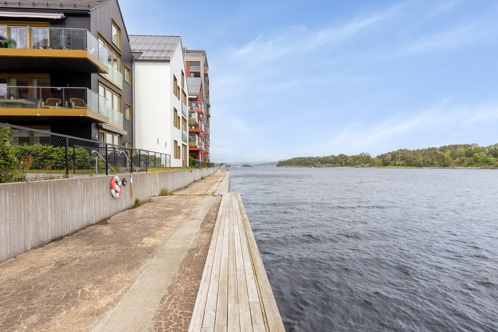 Det er en promenade langs sjøen med brygge og piknikbord. Galleribilde