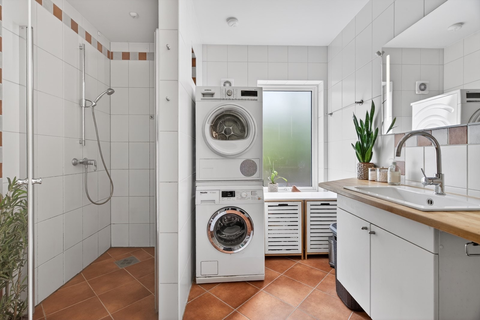 Badet i første etasje har flislagt gulv og vegger, dusjhjørne og opplegg for vaskesøyle. Galleribilde
